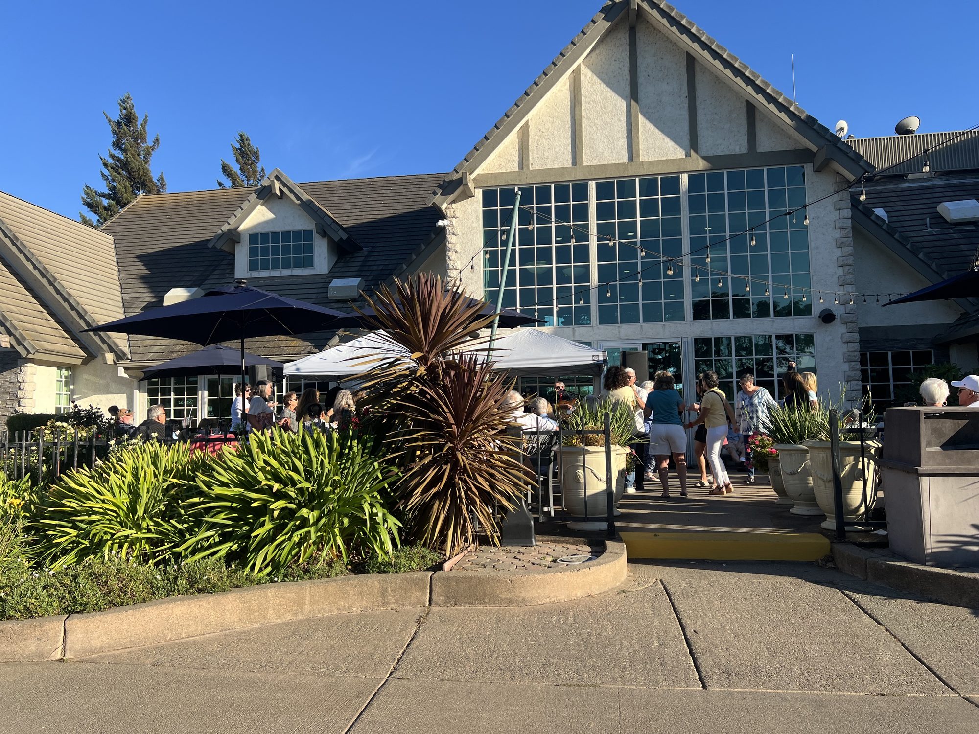 The clubhouse and patio at Paradise Valley Golf Course, string lights up and tables filling on a clear evening